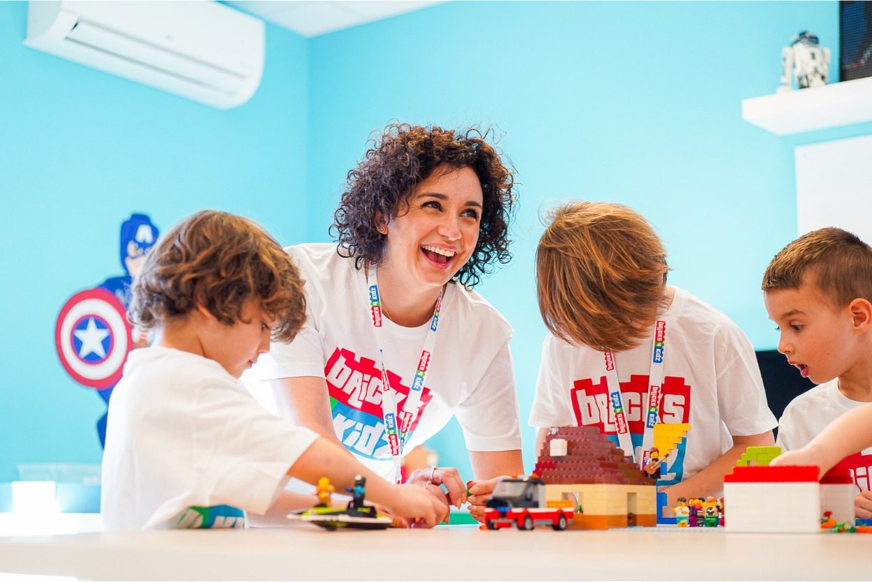 Animatrice et enfants autour d'une table de briques