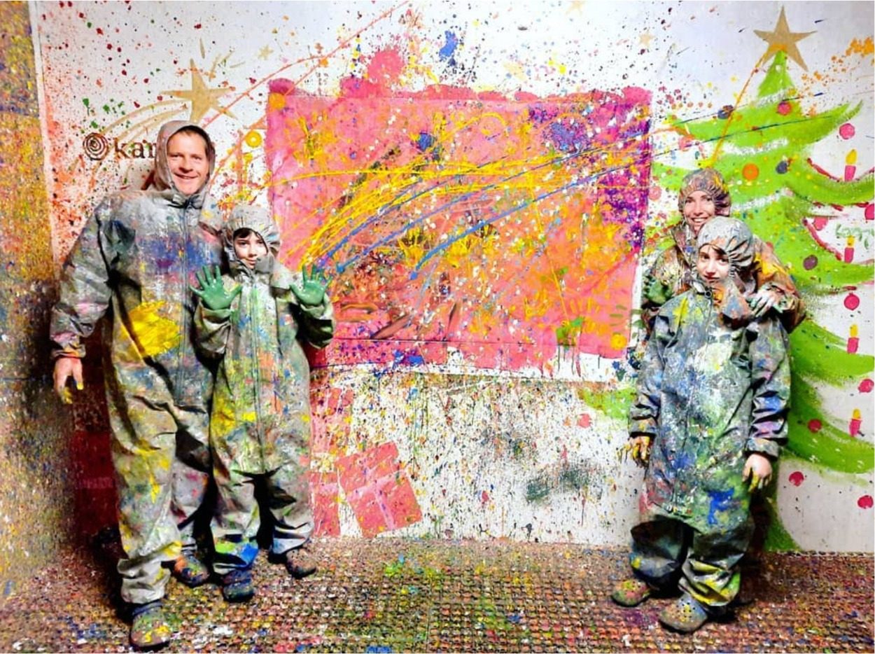 Room Jour : groupe en combinaison devant une toile éclaboussée de couleurs, salle éclairée